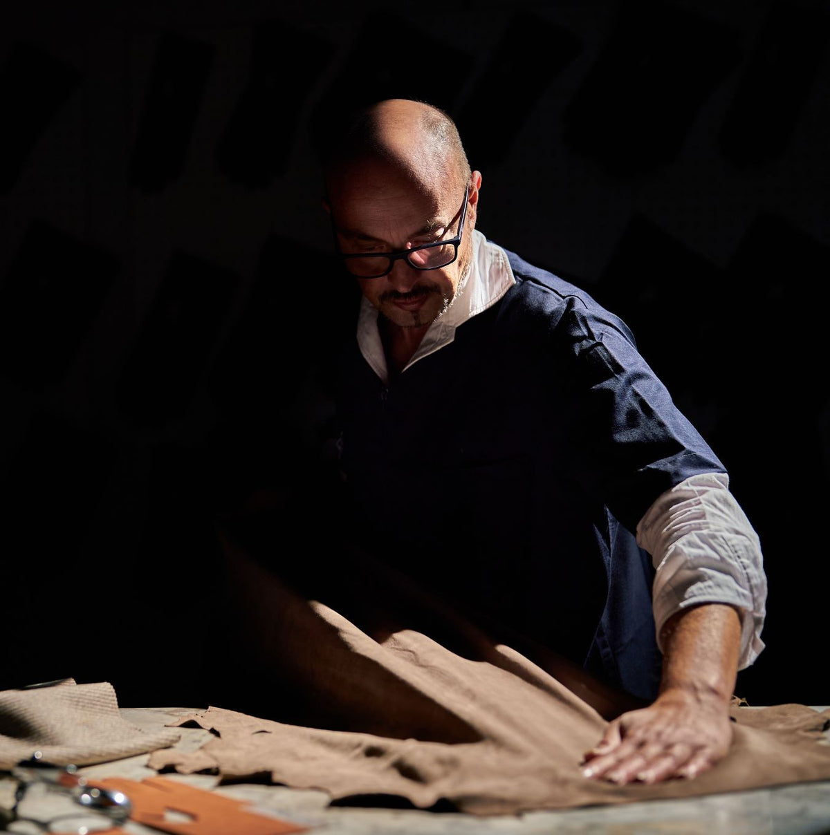 Alessandro Pellone examining rich brown leather, showcasing meticulous attention to detail in the luxury glove-making process.